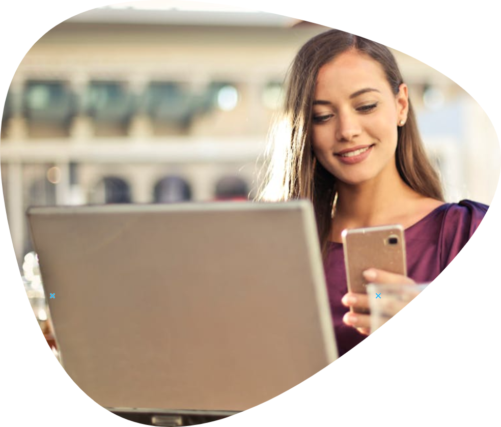 Photograph of woman using a computer with her phone in her hands