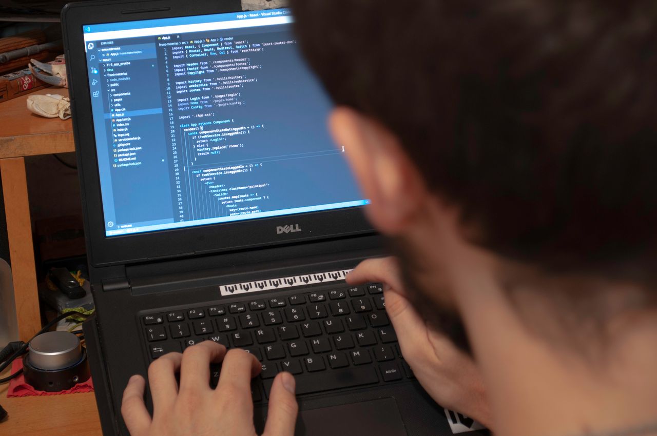 Photograph of a person using a computer with code on the screen