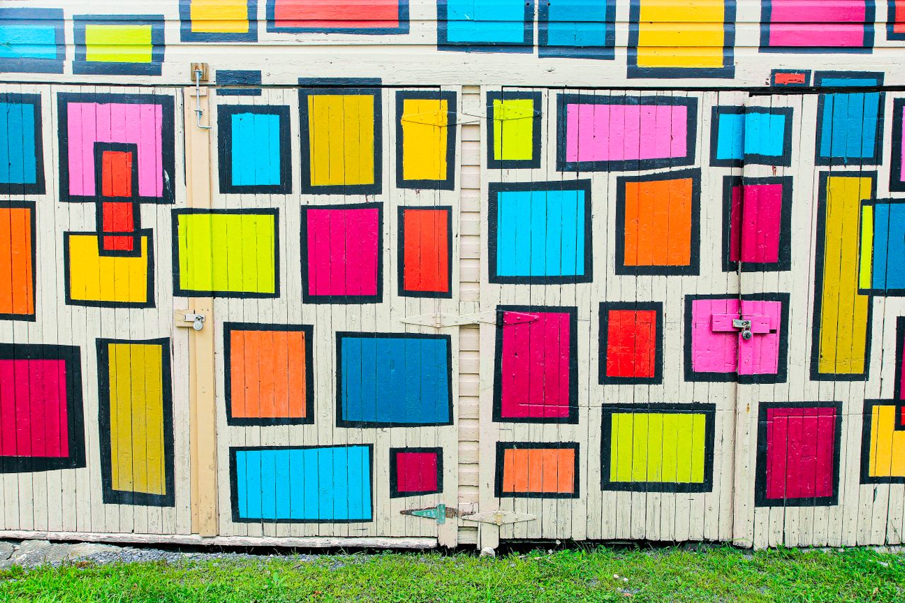 A photograph of a notepad showing drawings of square boxes coloured in, using different colours.