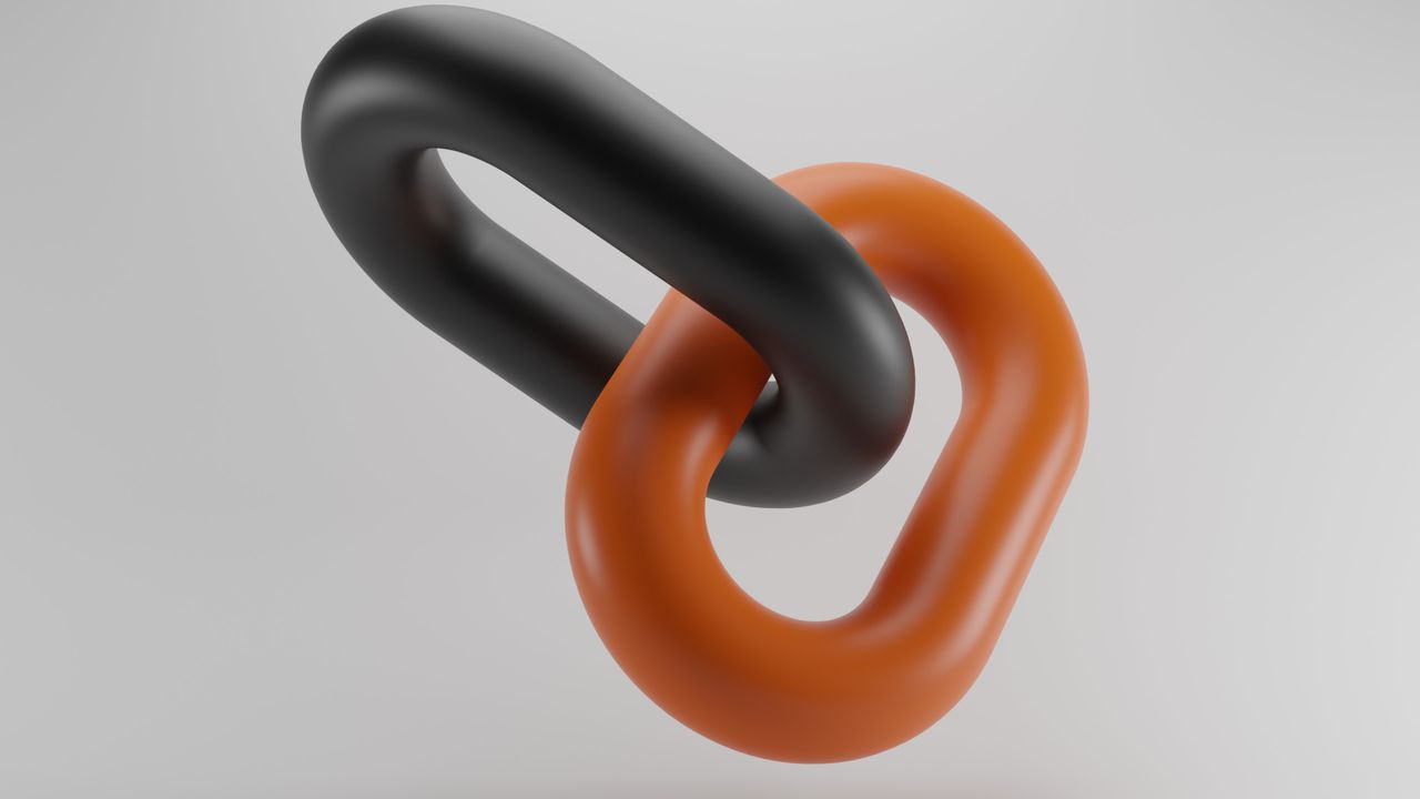 Photograph of two chain links interlinked, one is black, the other is orange.
