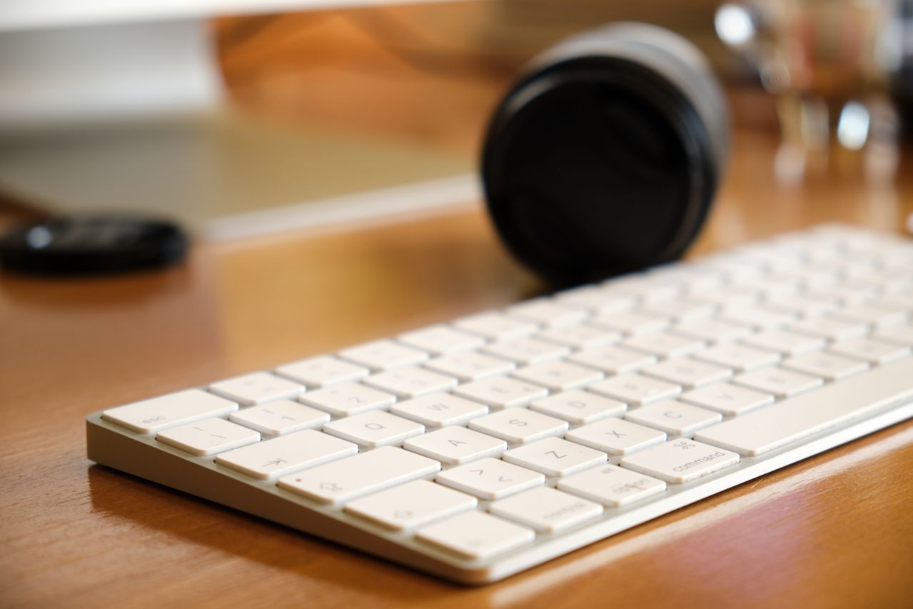 Photograph showing a white computer keyboard on a wooden desk