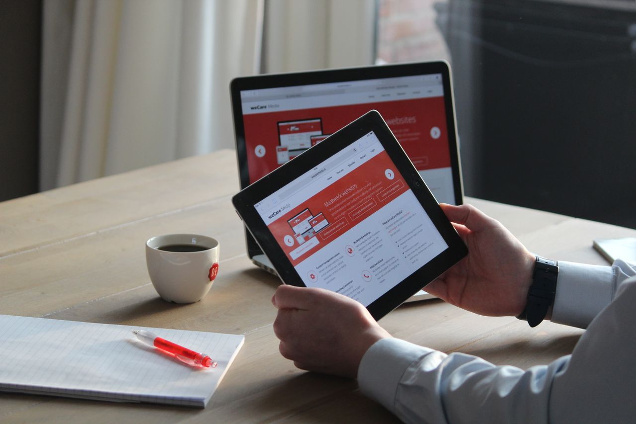 Photograph showing a laptop and a tablet with the same website showing on both screens.