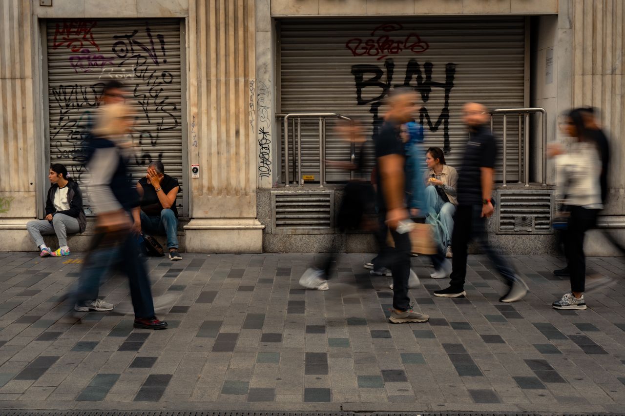Photograph showing a crowd of people with the people in the foreground blurred due to motion, the people in the background are clear